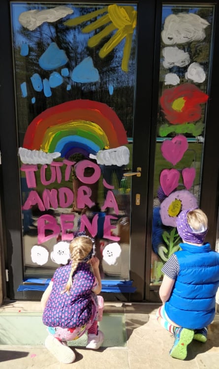 Children painting a door with the “andrà tutto bene” slogan