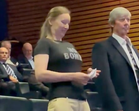 Two people standing up with others sitting behind them