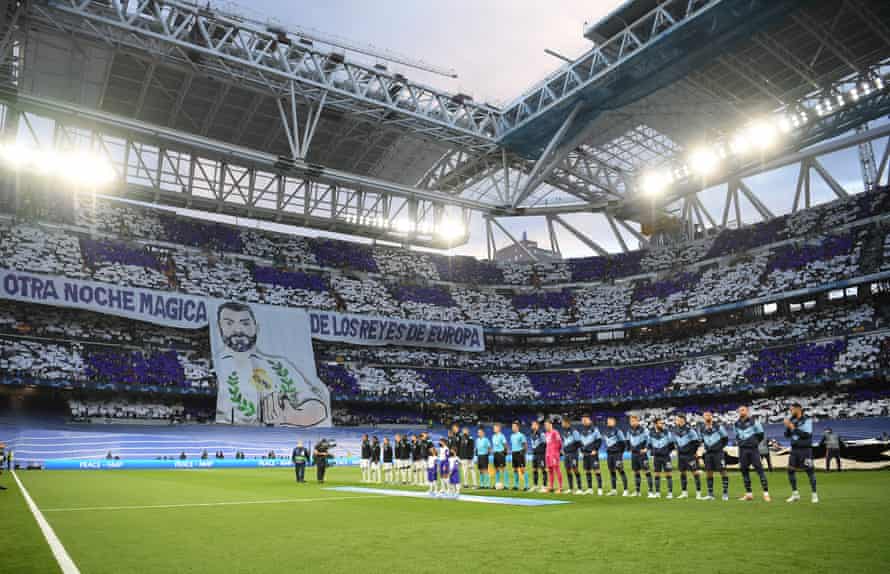 The players line up ahead of kick-off as the Real Madrid fans display a banner to Karim Benzema reading “Another Magic Night from the Kings of Europe”.