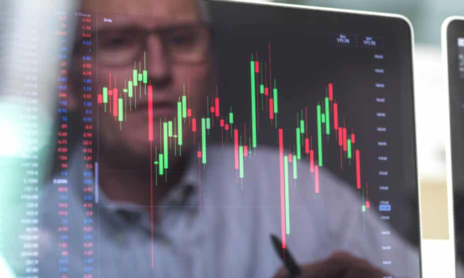 Reflection of a stock trader viewing the performance of a company share price on screen<br>GettyImages-1208356039