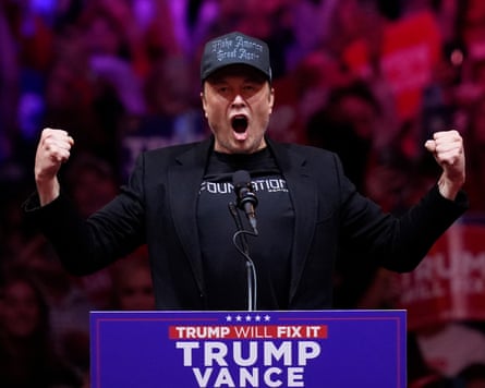 Elon Musk raising two fists behind a Trump-Vance lectern