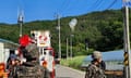 Soldiers stand near a white balloon caught on electricity wires