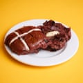 An M&S red velvet filled hot cross bun, sliced, toasted and buttered, on a white plate