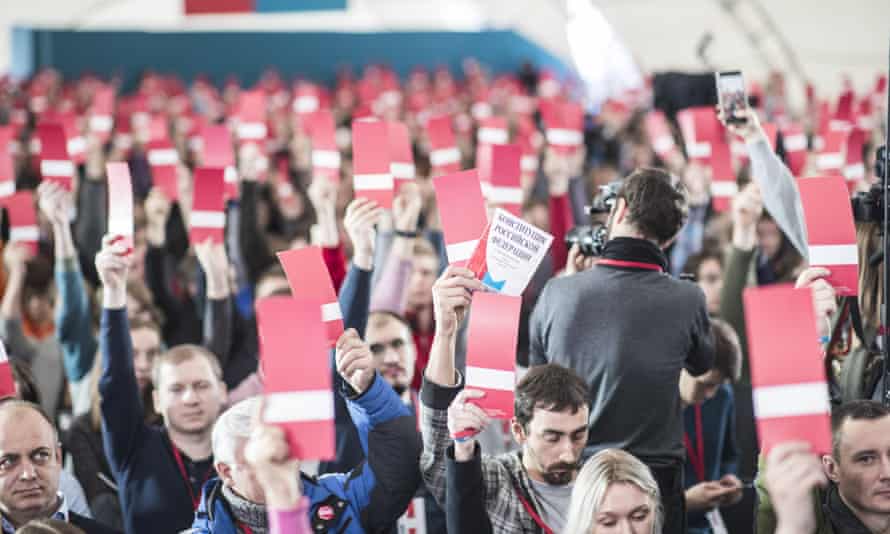 A crowd of people, all waving red and white cards
