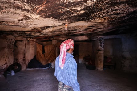 A man, seen from behind, inside a sparse cave dwelling