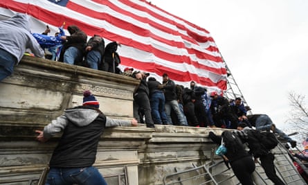 People use barricades as ladders as they storm the US Capitol.