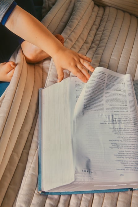 A baby’s hand plays with the corner of an open Bible