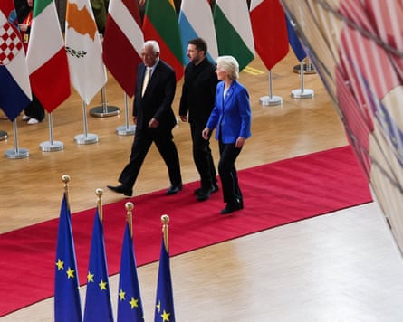 Zelenskiy, von der Leyen and Costa walk a red carpet past rows of EU and national flags