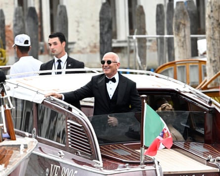 Jeff Bezos vistiendo traje y gafas de sol, y sonriendo, mientras está en un pequeño barco en Venecia.