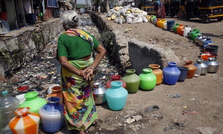 An elderly woman waits to fill pots for filling drinking water at a slum area in Mumbai.