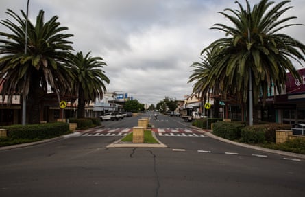 A wide regional town street with palm trees on either side