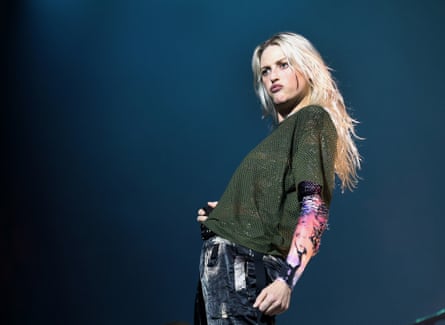 Emily Armstrong wears a khaki jumper and leans back as she performs on stage