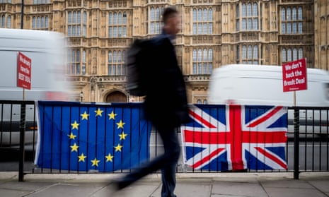 A pedestrian walks past EU and British Flags on railings outside the Houses of Parliament