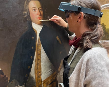 A woman with microscopic glasses works on the painting.