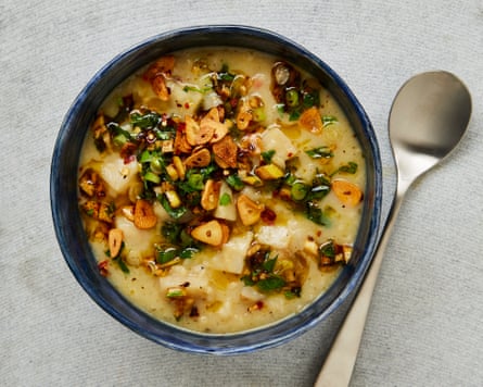 A bowl with a pale coloured soup and garlic chunks on top