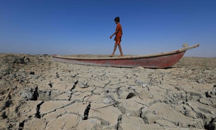 A boy walks on a boat left lying on the dried bed of a section of Iraq’s receding southern marshes of Chibayish in Dhi Qar province.
