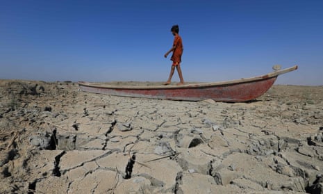 A boy walks on a boat left lying on the dried-up bed of a section of Iraq's receding southern marshes