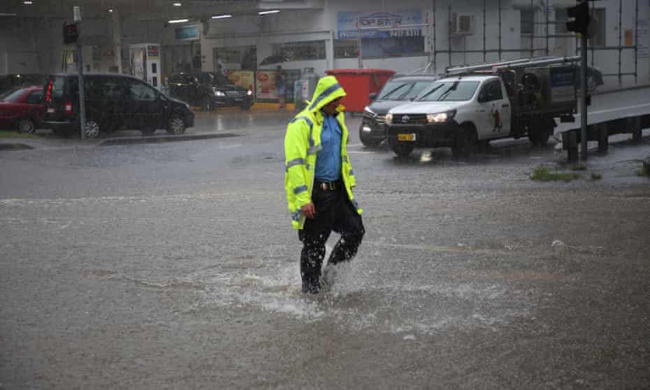 Police man walks through flooded intersection 