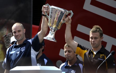 Geelong’s Tom Harley and Hawthorn’s Sam Mitchell hold aloft the AFL premiership trophy at the grand final parade in 2008.