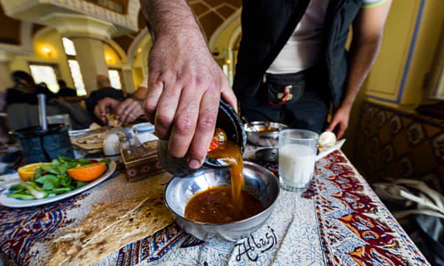 Waiter serving lunch, Iranian style, pouring dizi stew into a bowl.