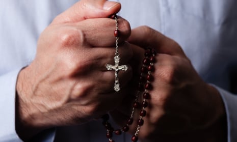 Someone holds  a rosary with a Crucifix