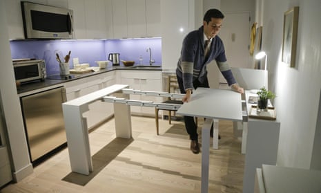 Christopher Bledsoe demonstrates a desk that expands into a dining table that can seat up to 12 people inside one of the increasingly popular micro-apartments in New York.