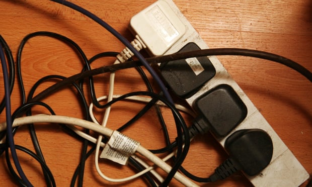 Four plugs, three black and one white, in an adaptor amid a tangle of wires