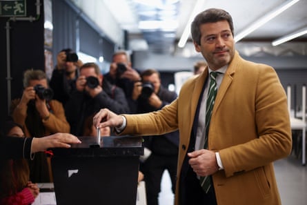 Man in camel-coloured jacket puts his vote into a ballot box