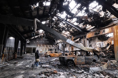 भारी क्षतिग्रस्त इमारत के अंदर मलबे और मलबे के बीच खड़ी एक महिला।