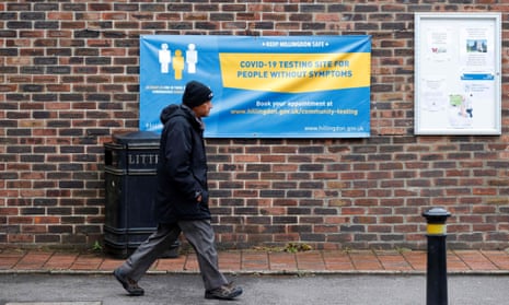 A man walks past a banner of a coronavirus testing site in Hillingdon, England.