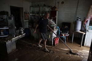 A man removes mud at the entrance of a restaurant in a flooded street in Taishitun, in the district of Miyun.
