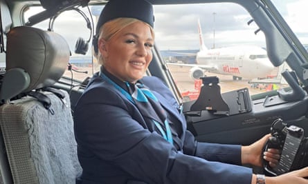 Karlene Warner, dressed in a flight attendant’s uniform, smiling and posing at the controls of a plane.