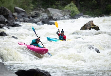 Two kayakers coming down white water. Very active scene.