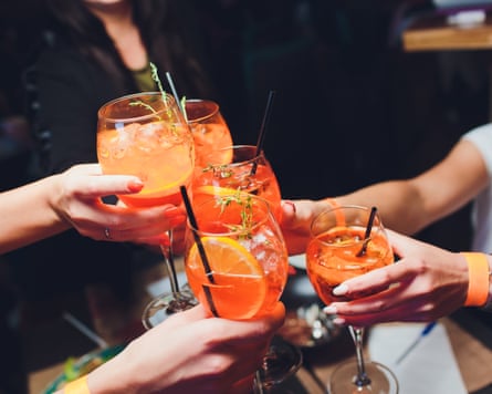 Women raising glasses of spritz at the dinner table