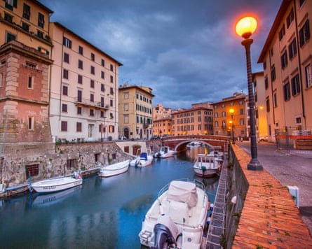 Tall buildings by a canal with boats.