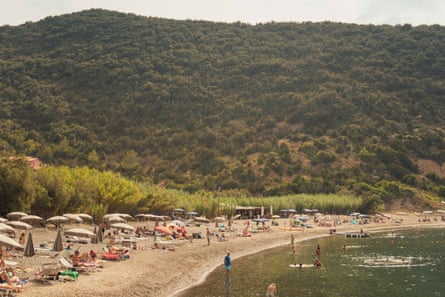 A long, flat beach with shrub-covered hills behind