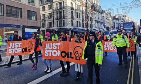 Just Stop Oil protestors block traffic in London while police officers observe.