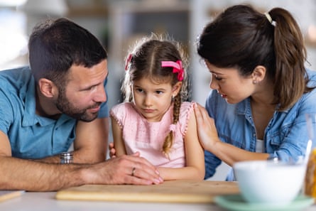 Man and woman at a table talking to a small girl sitting between them