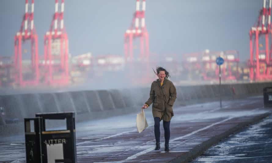 Mulher tenta evitar respingos do mar agitados pelo vento e pelas ondas em New Brighton, Merseyside, enquanto o Reino Unido se prepara para a chegada de Storm Barra.