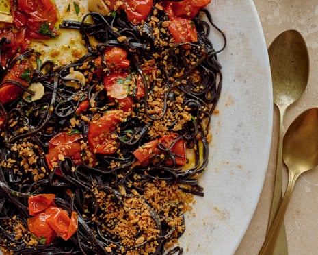 Chris Leach's squid Ink spaghetti with anchovies, cherry tomato and pangrattato on a platter with cutlery and drinks nearby