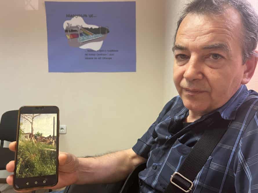 Vladimir Korchma shows photos of a destroyed apartment building in Mariupol.