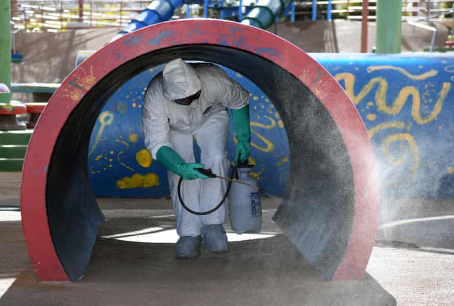 A Las Vegas maintenance worker disinfects playground equipment.