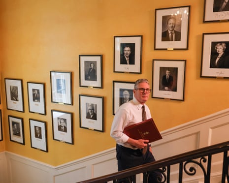 Keir Starmer walks up the staircase of 10 Downing Street, with portraits of previous prime ministers on the walls.