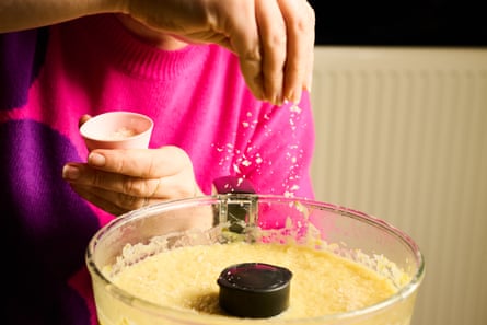 Food processor full of blended soup. A hand is sprinkling salt into the food processor