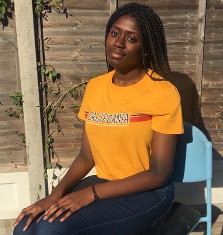 Oreoluwa Adeyoola wearing an orange T-shirt and sitting on a blue chair in a garden.