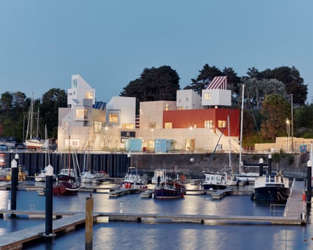 A modern cubist building overlooking a harbour with boats.