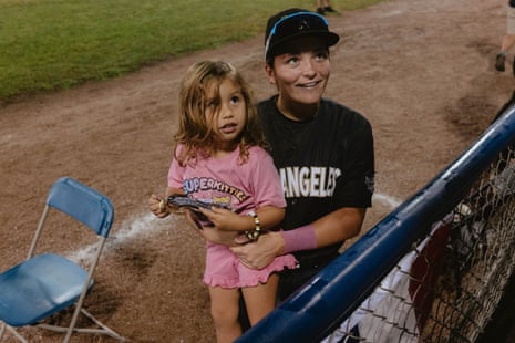 A baseball player holds her young niece on the field after a game