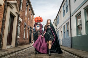 A couple in Halloween costumes walk along a street