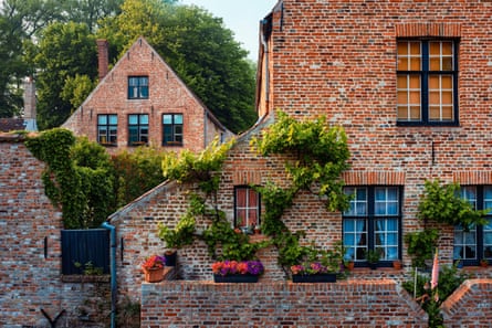 Red brick buildings with steep roofs, multi-paned windows and flower boxes on a wall in front of them