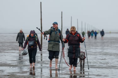 Image 29: People walk a route to Lindisfarne across tidal mud
